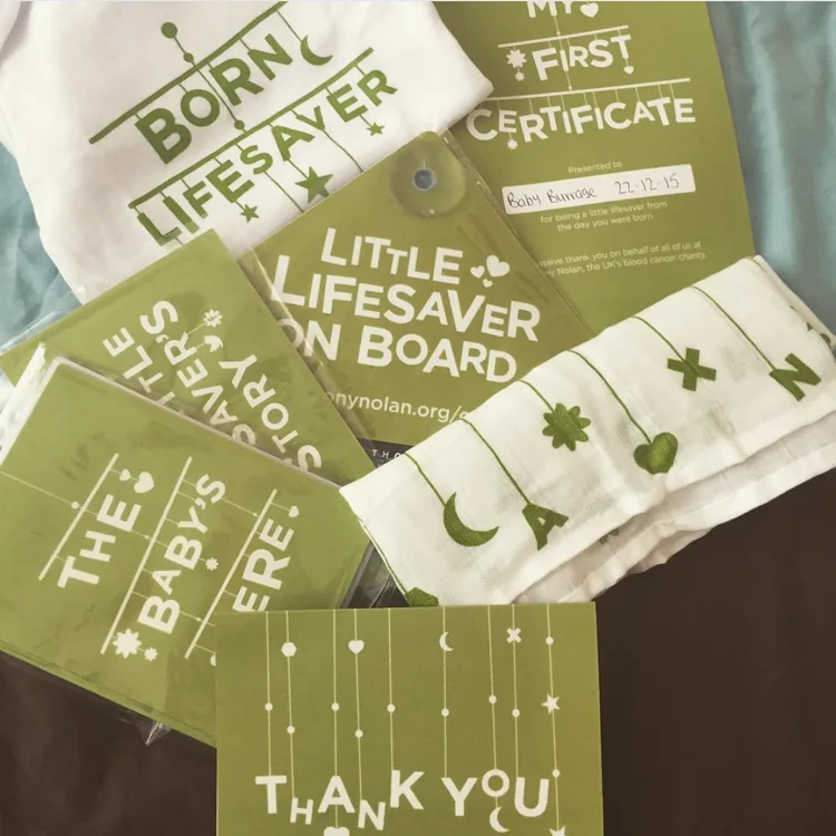 The bundle laid out: babygrow, car sign, postcards, muslin and certificate