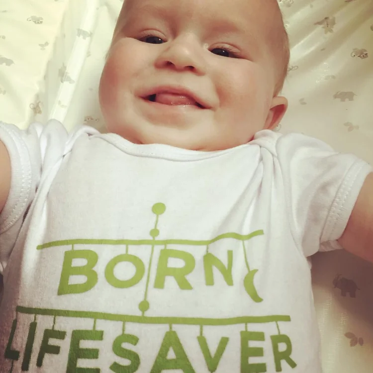 Close-up of a smiling baby in a &lsquo;Born lifesaver&rsquo; babygrow
