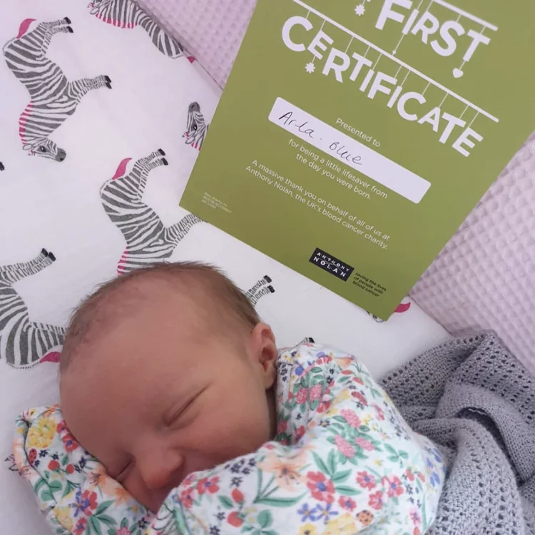 Sleeping newborn beside a named &lsquo;My first certificate&rsquo;