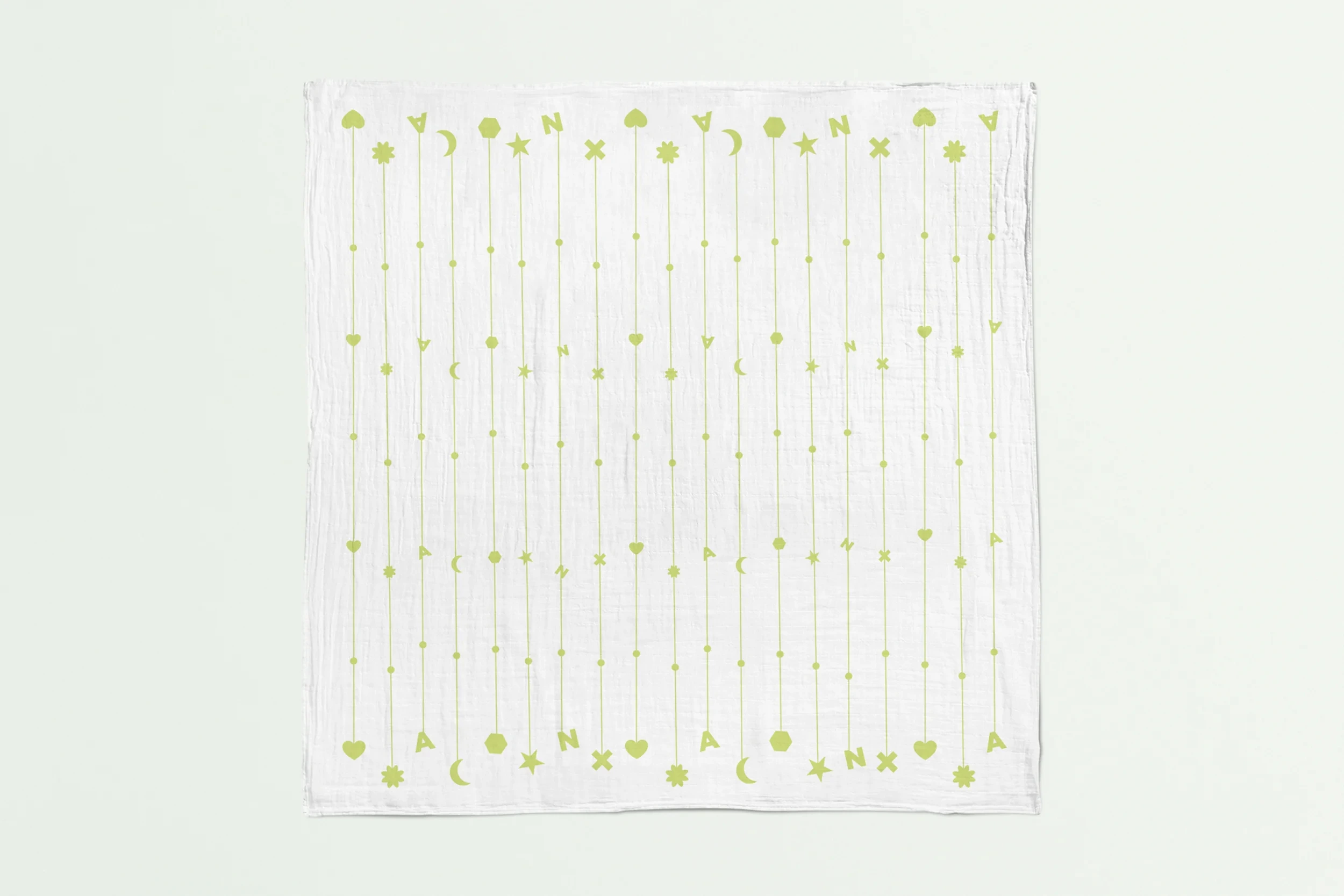 White muslin square with a green pattern of stars, moons and hearts
