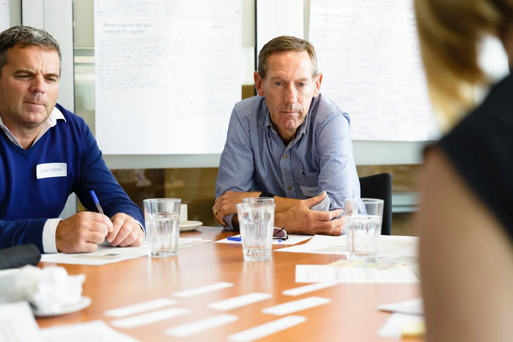 Patient information panel members discussing content around a table