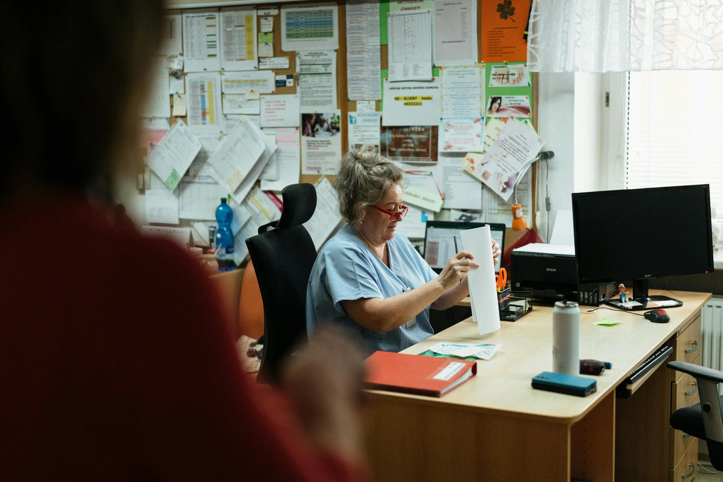 Healthcare professional reading a document at a desk in a clinic office