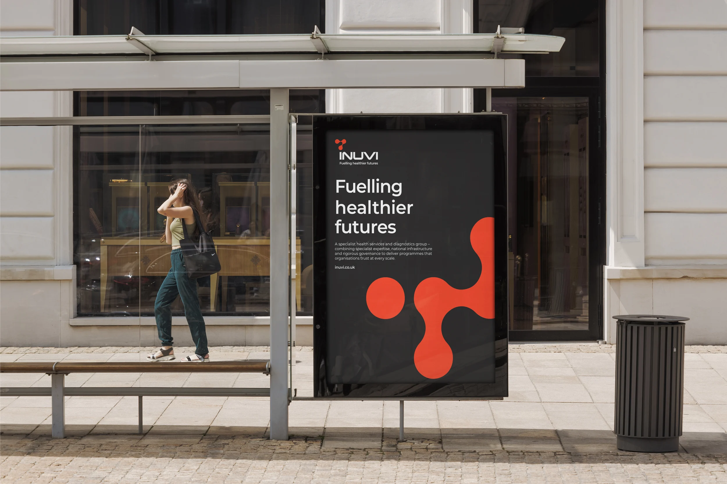 Inuvi &lsquo;Fuelling healthier futures&rsquo; poster at a bus stop, with the red molecular shape on a dark grey background