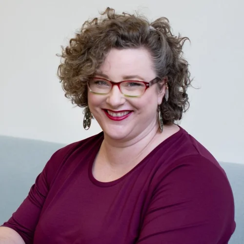 Persona photo: a smiling woman with curly hair and glasses, representing the HR Director
