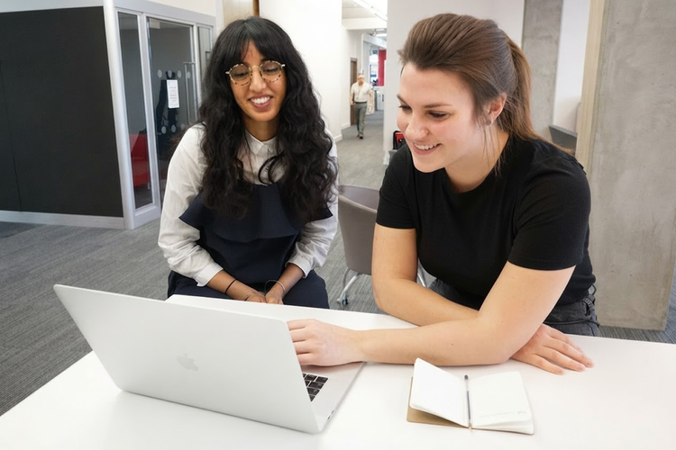 Two women smiling during a usability testing session at a laptop